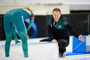 Erik Wink steekt zijn hand uit om zijn schaatser te prijzen