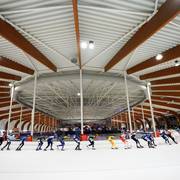 Het marathonpeloton raast door de bocht in de Elfstedenhal in Leeuwarden