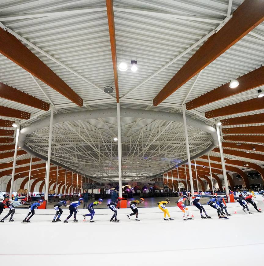 Het marathonpeloton raast door de bocht in de Elfstedenhal in Leeuwarden